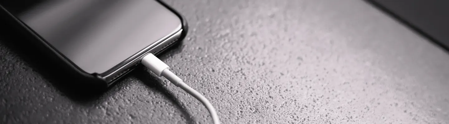 black smartphone with charger cord connected